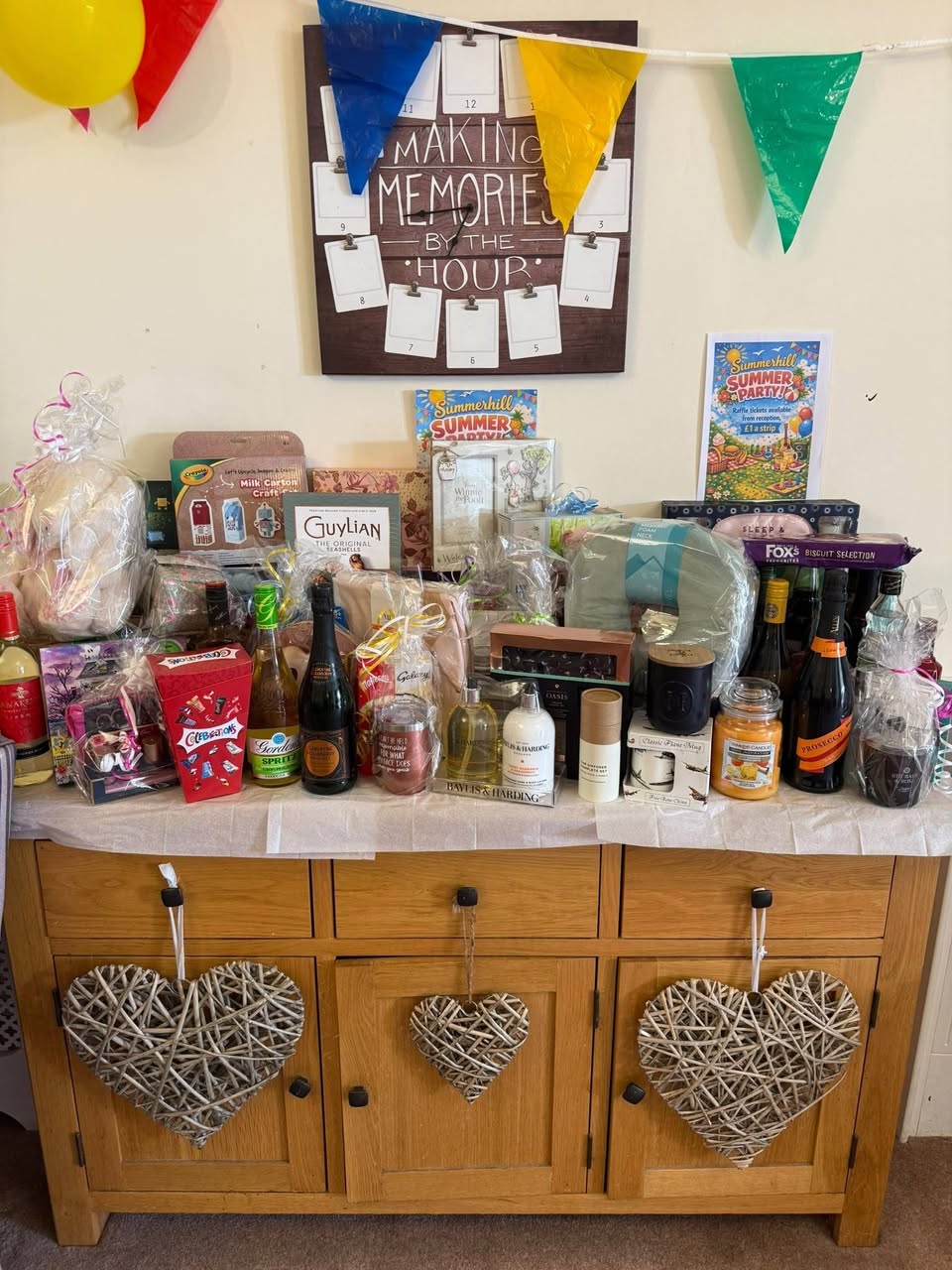Table of Summer Party gift hampers, drinks and treats beneath a Making Memories by the Hour sign and Summerhill party poster.